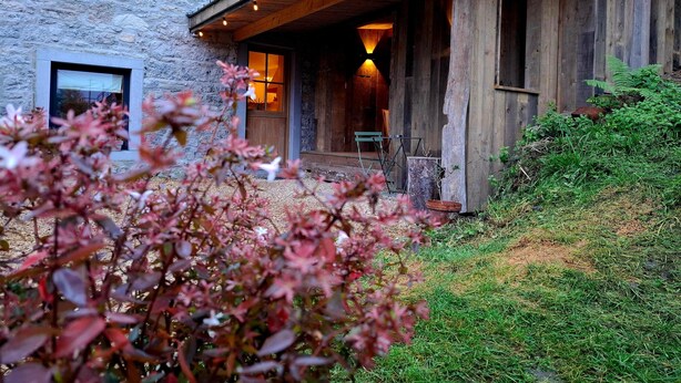 A rustic stone building with a wooden porch and a window. - La Tanière - Nature and relaxation gîte (Durbuy)