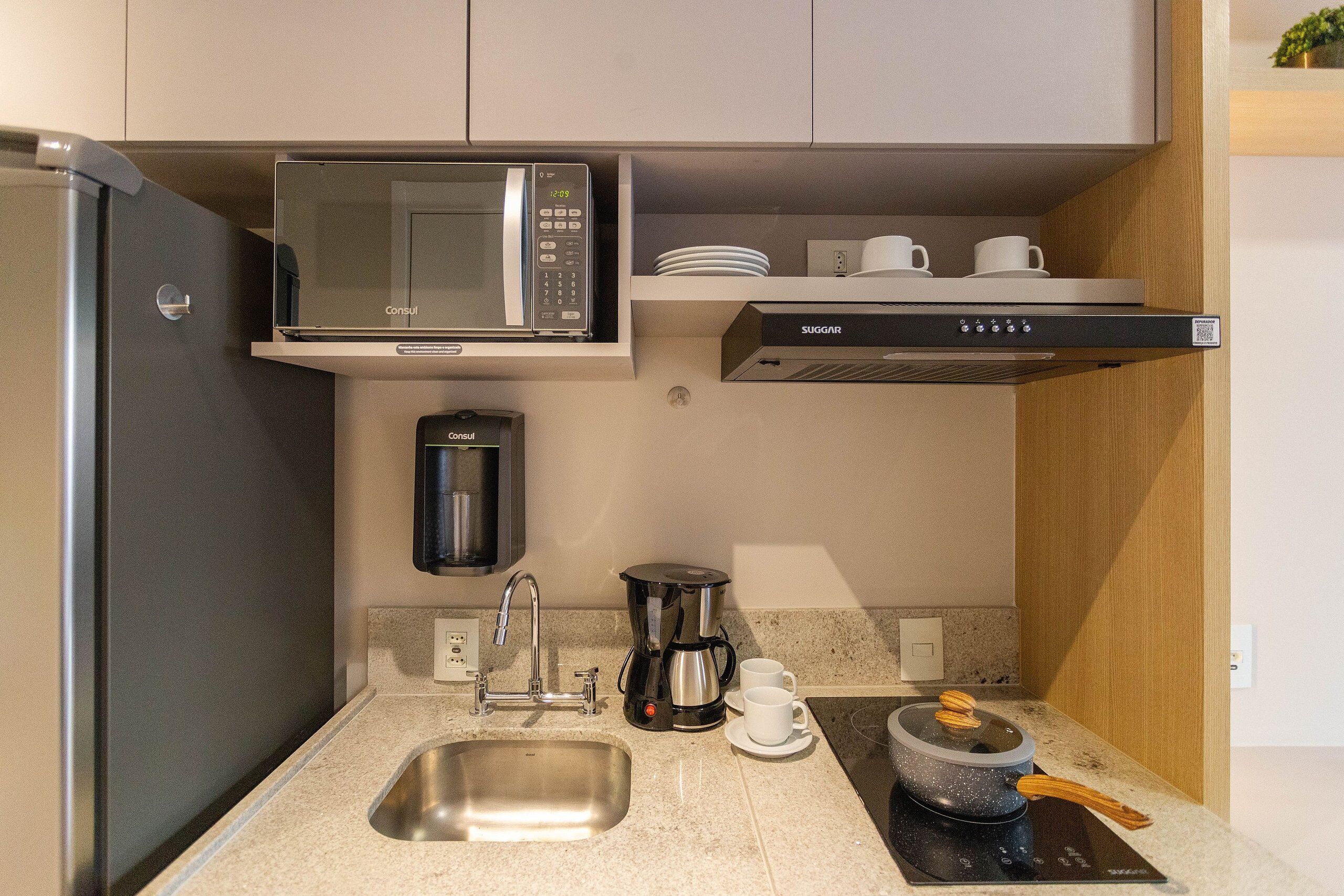 Una cocina moderna con un lavaplatos de acero inoxidable, cafetera, microondas y estufa.