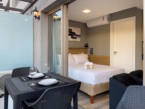 A hotel room with a bed, a table with a glass, and a chair.