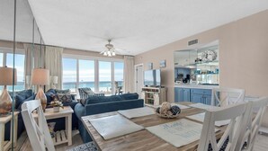 Un salón moderno con una mesa de comedor de madera, sofás azules y vistas al océano.