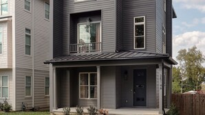 A two-story residential building with a dark gray exterior, a front porch, and a visible garage door. - Ultimate Bach 10min to DT, Insta Walls Every Room (Nashville)