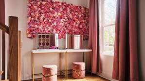 A room with a wooden floor, a white desk with gold legs, a pink floral wall art, and a window with pink curtains. - Ultimate Bach 10min to DT, Insta Walls Every Room (Nashville)