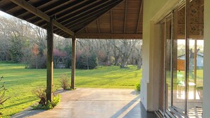 Un patio abrité avec un banc, donnant sur un champ verdoyant, et un mur de pierre en arrière-plan.