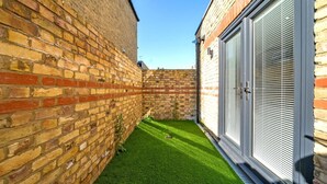 A narrow courtyard with a brick wall on one side and a garage door on the other.
