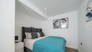 A bedroom with a bed, nightstand, and two framed pictures on the wall.