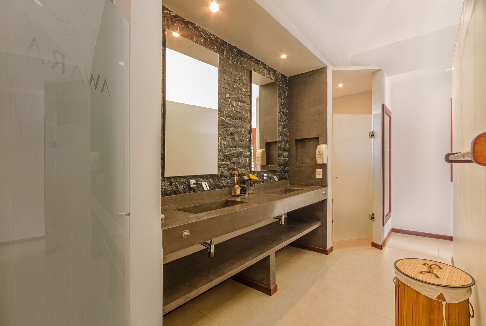A modern bathroom with a double sink, a large mirror, and a stone accent wall.