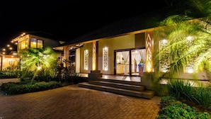 A modern hotel with a well-lit entrance, a brick pathway, and lush greenery. - Awara Pousada Boutique (São Miguel do Gostoso)