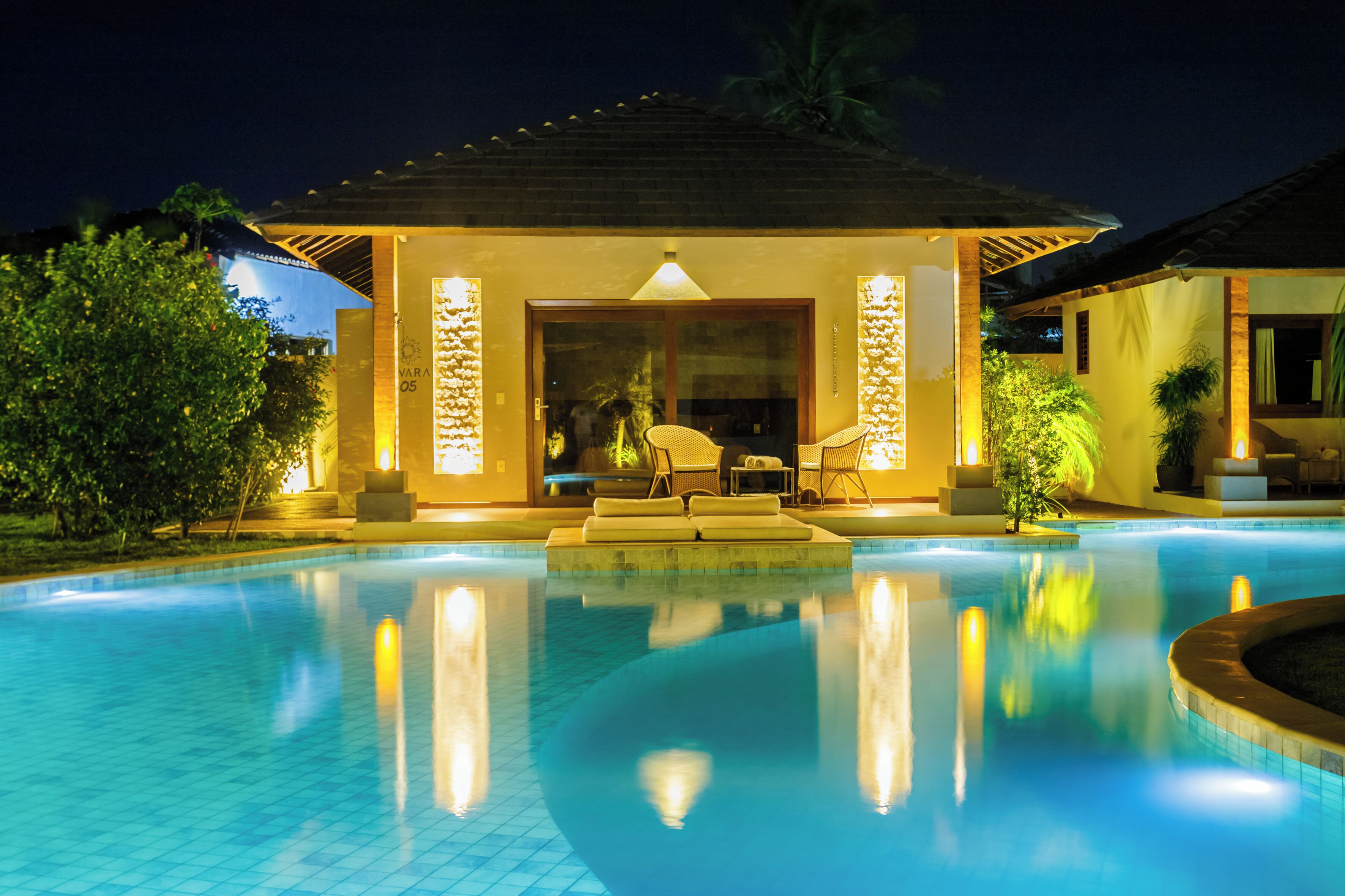 A swimming pool with a sunken seating area and a covered lounge with a view of the pool.