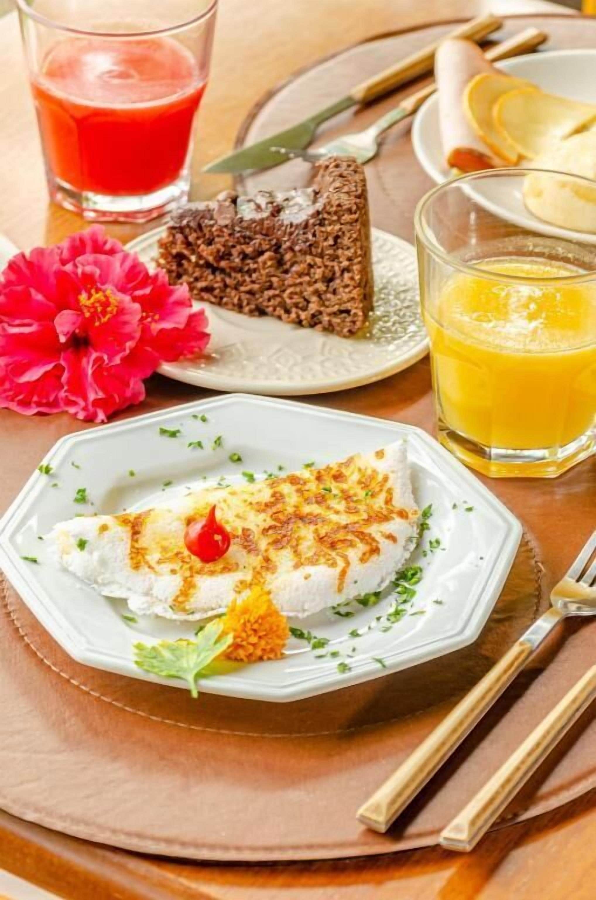 Une assiette contenant un morceau de poisson blanc, une part de gâteau et un verre de jus d’orange.