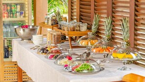 A buffet table with various food items, including fruits and nuts, covered with glass domes. - Awara Pousada Boutique (São Miguel do Gostoso)