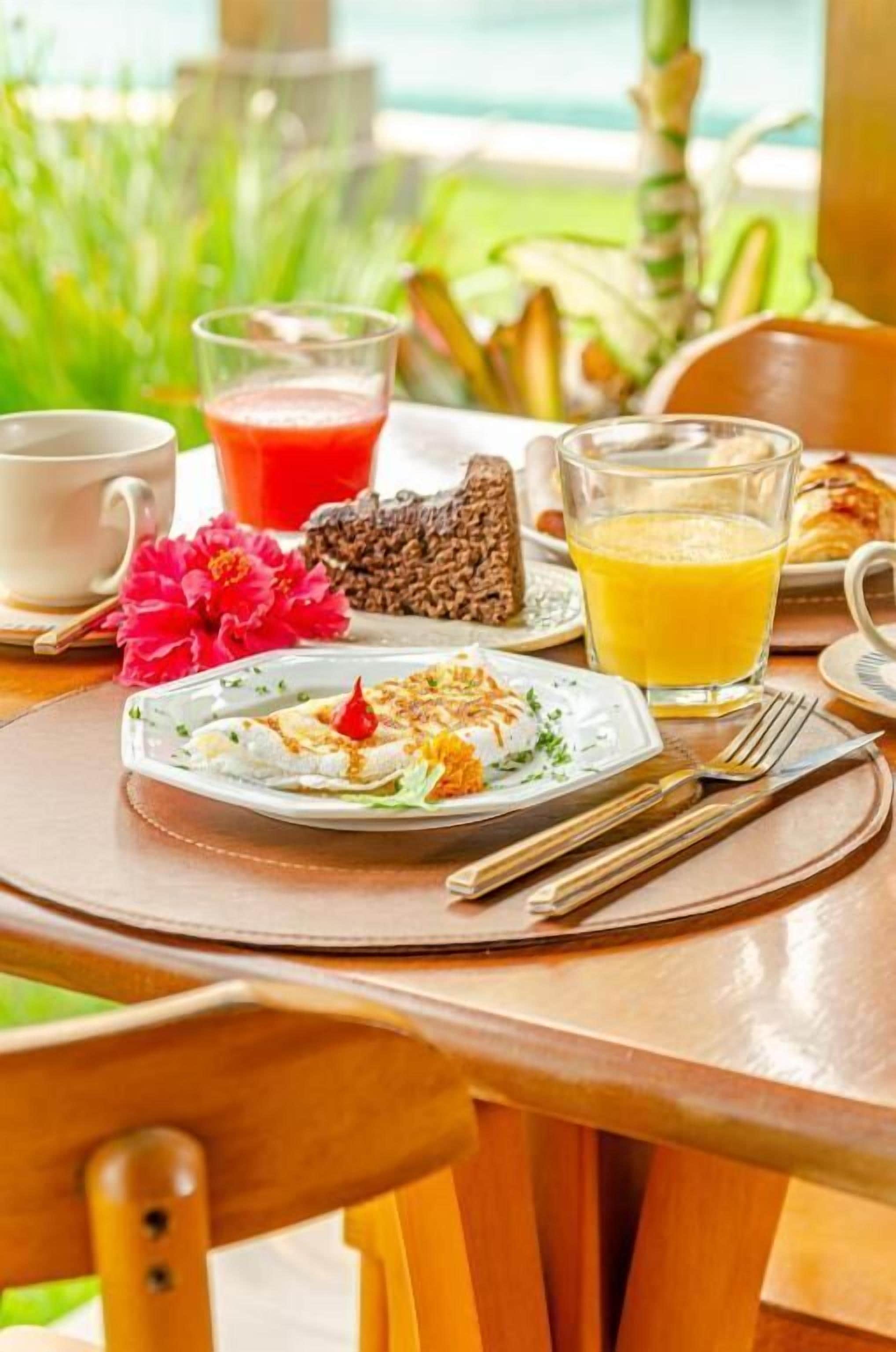 Un desayuno con un plato de comida, un vaso de jugo de naranja y una taza de café sobre una mesa de madera.
