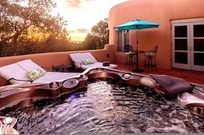 A hot tub with lounge chairs and a table, surrounded by a peach-colored building with a glass door. - Villa Namaste Mountain View Retreat Private Casita Santa Fe Los Alamos (Santa Fe)