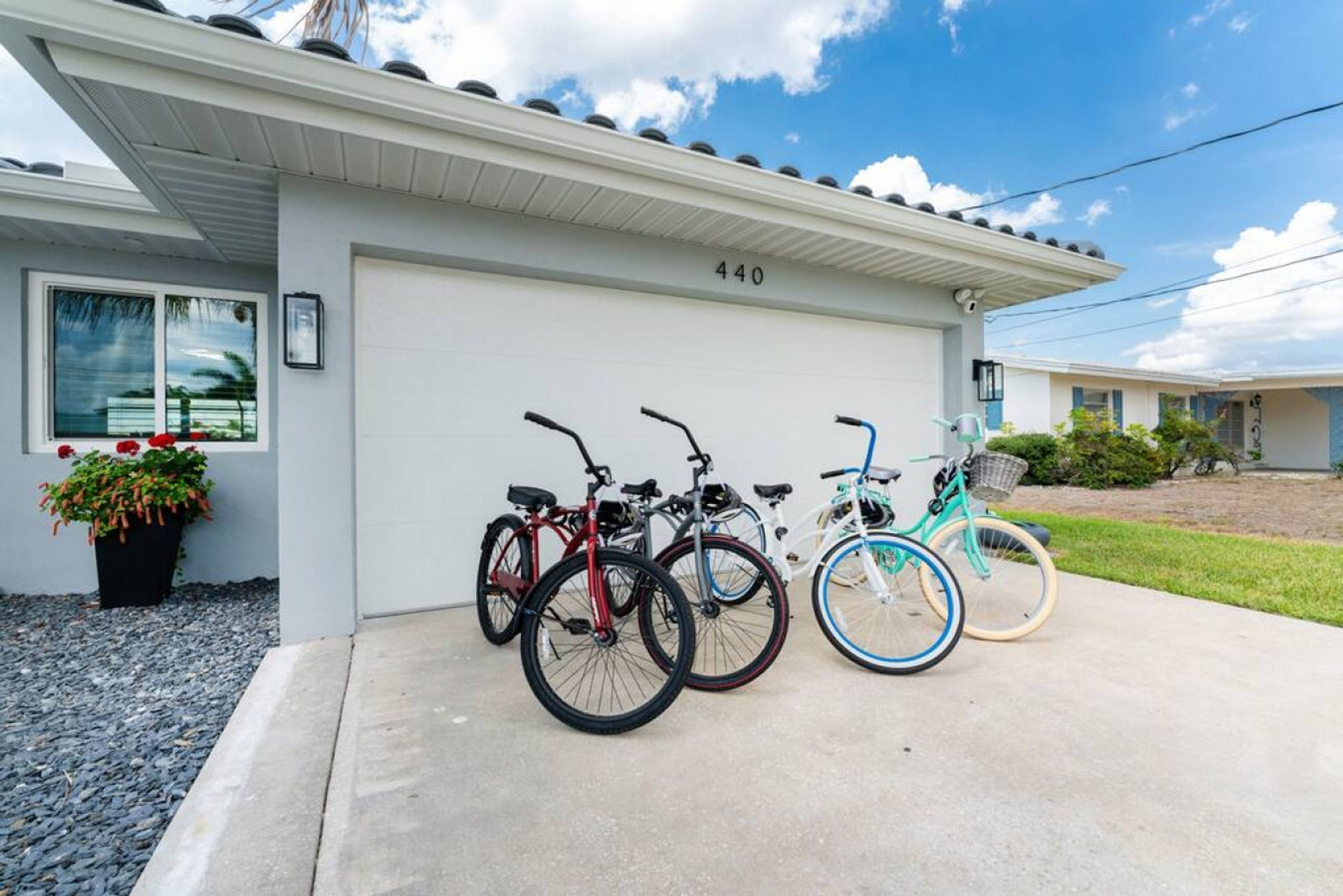 A residential garage with four bicycles parked outside.