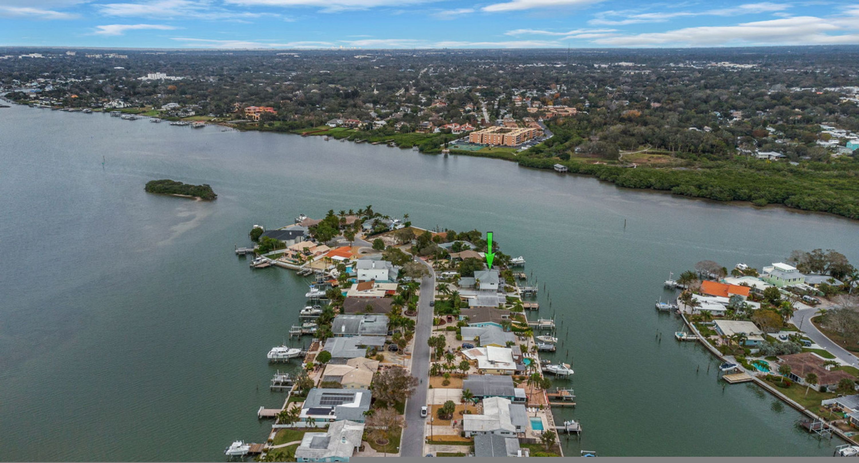An aerial view of a marina with boats docked, surrounded by residential buildings and greenery.