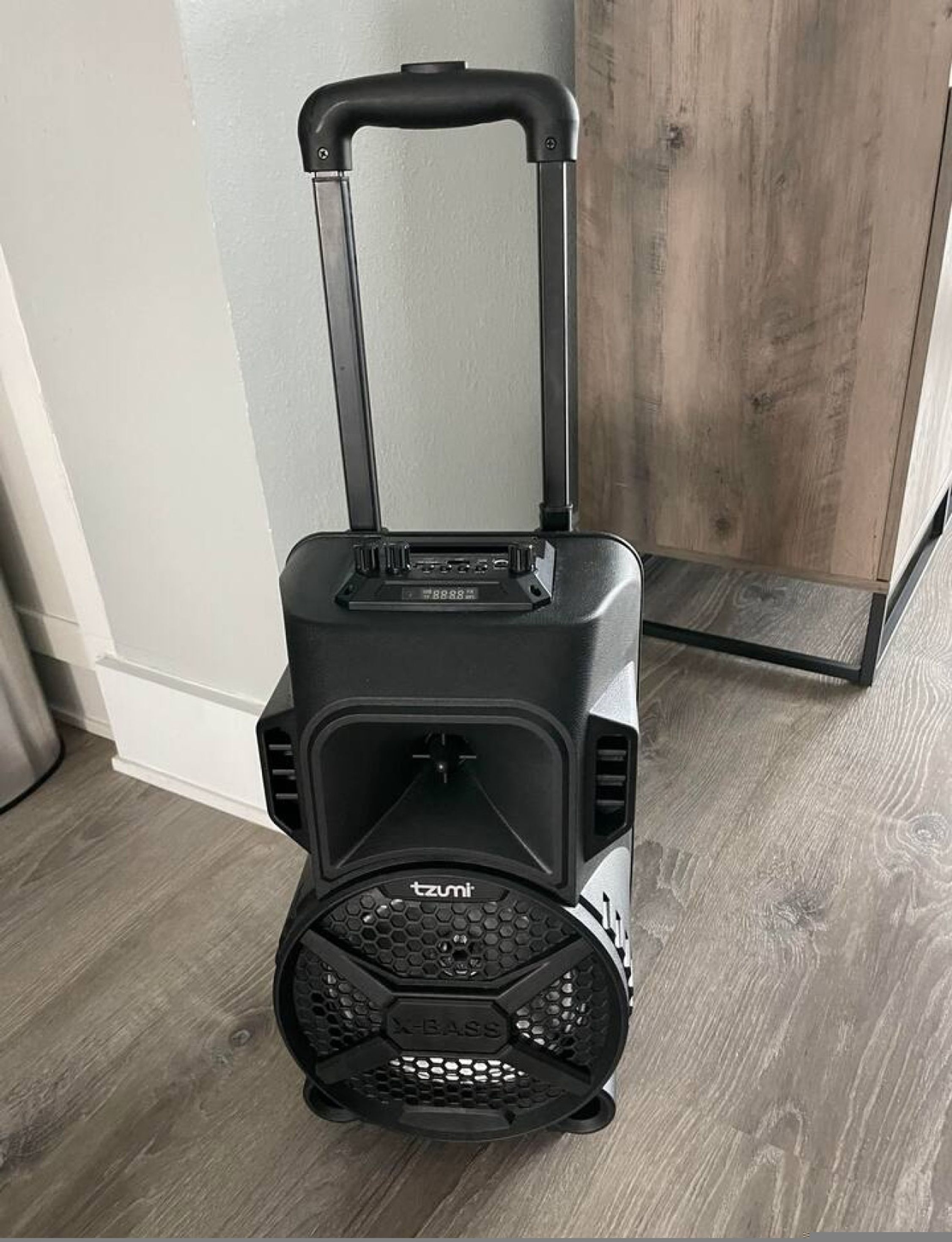 A black suitcase with wheels and a handle, featuring a digital display and a brand name "tzu" on the front.