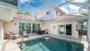 A pool area with a glass enclosure, outdoor furniture, and a patio with a table and chairs. - Dog Friendly Walk to Fishermen s Village Pool (Punta Gorda)