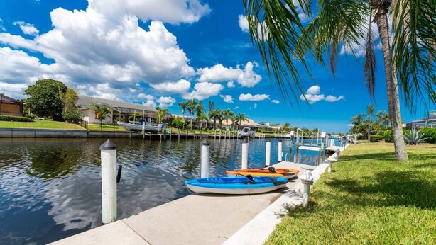 A marina with kayaks docked, a calm water body, and a clear sky. - Dog Friendly Walk to Fishermen s Village Pool (Punta Gorda)
