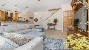 A spacious living room with a large sectional sofa, a ceiling fan, and a kitchen area in the background. - Dog Friendly Walk to Fishermen s Village Pool (Punta Gorda)