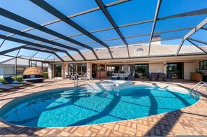 A covered outdoor swimming pool with a patio area, lounge chairs, and a seating area with a table and chairs. - Villa Tropical Waterfront Luxury Retreat Panoramic Water Views Pool Spa (Punta Gorda)