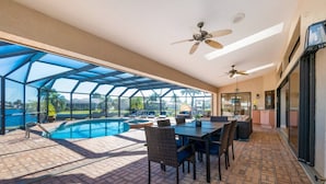 A covered outdoor area with a pool, dining table, chairs, and ceiling fans. - Villa Tropical Waterfront Luxury Retreat Panoramic Water Views Pool Spa (Punta Gorda)