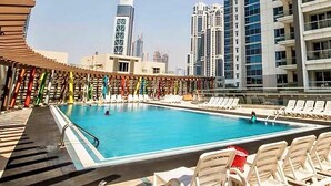 A swimming pool with lounge chairs, surrounded by tall buildings. - Lux BnB I Executive Tower I Business Bay (Dubai)