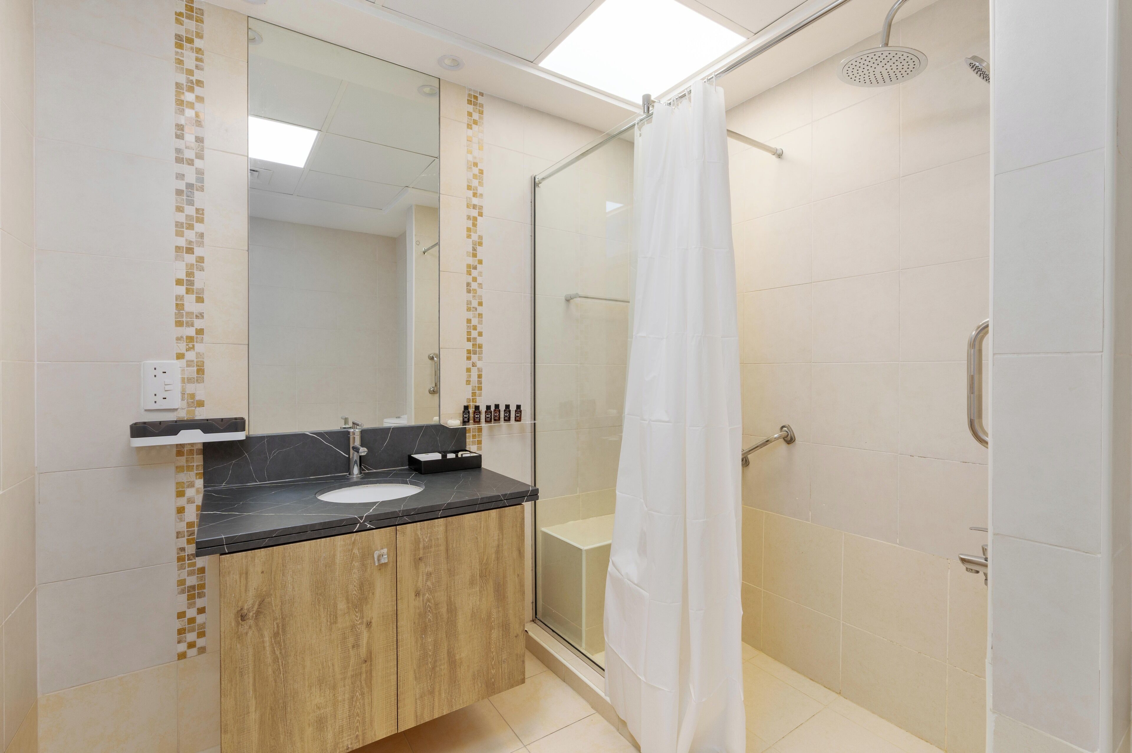 A modern bathroom with a glass shower enclosure, a wooden vanity, and a white sink.