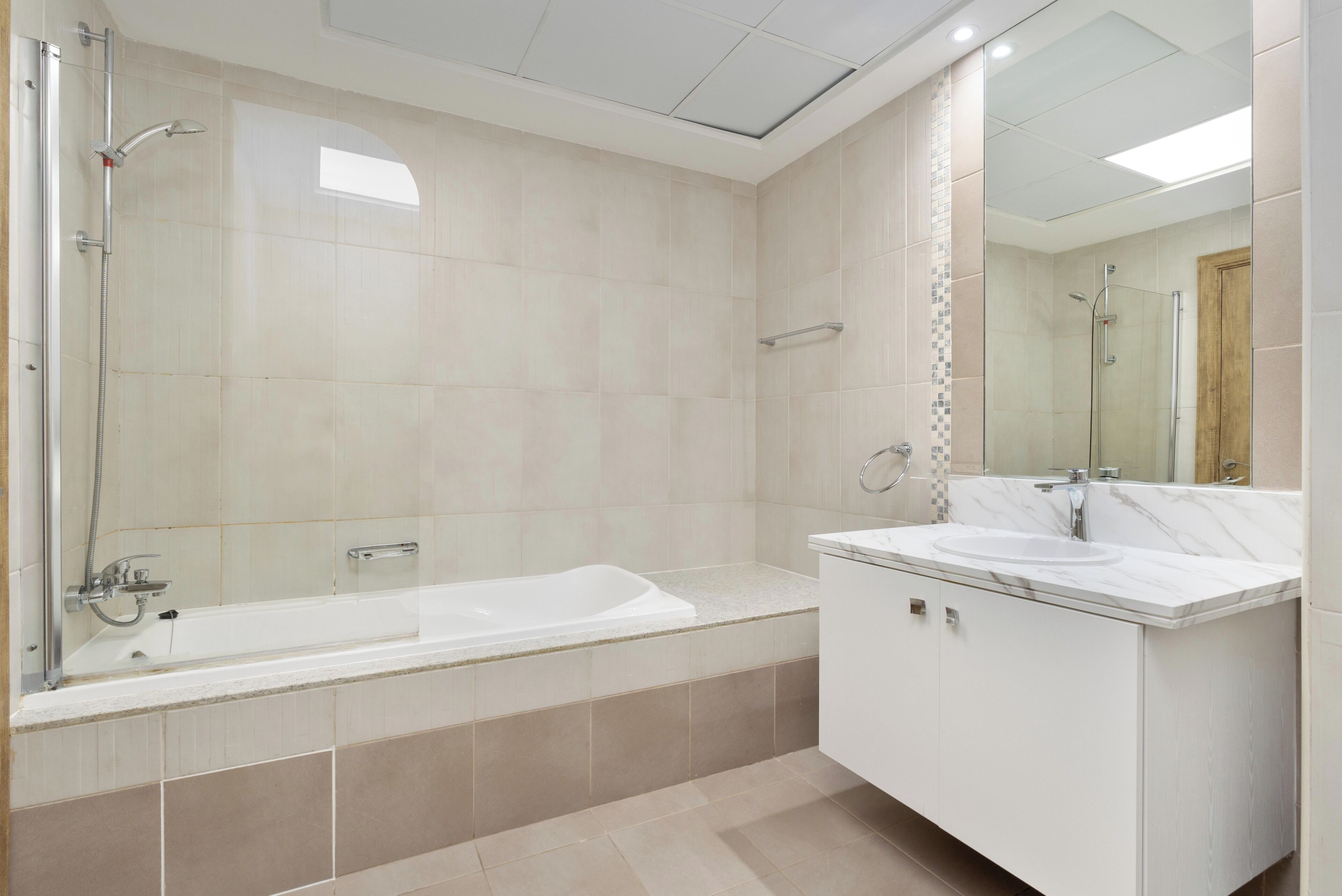 Une salle de bain moderne avec une baignoire, un grand miroir et un meuble-lavabo.