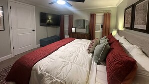 Ein Schlafzimmer mit einem großen Bett, einem Deckenventilator, einem Fernseher, einer Kommode und gerahmten Kunstwerken an den Wänden.