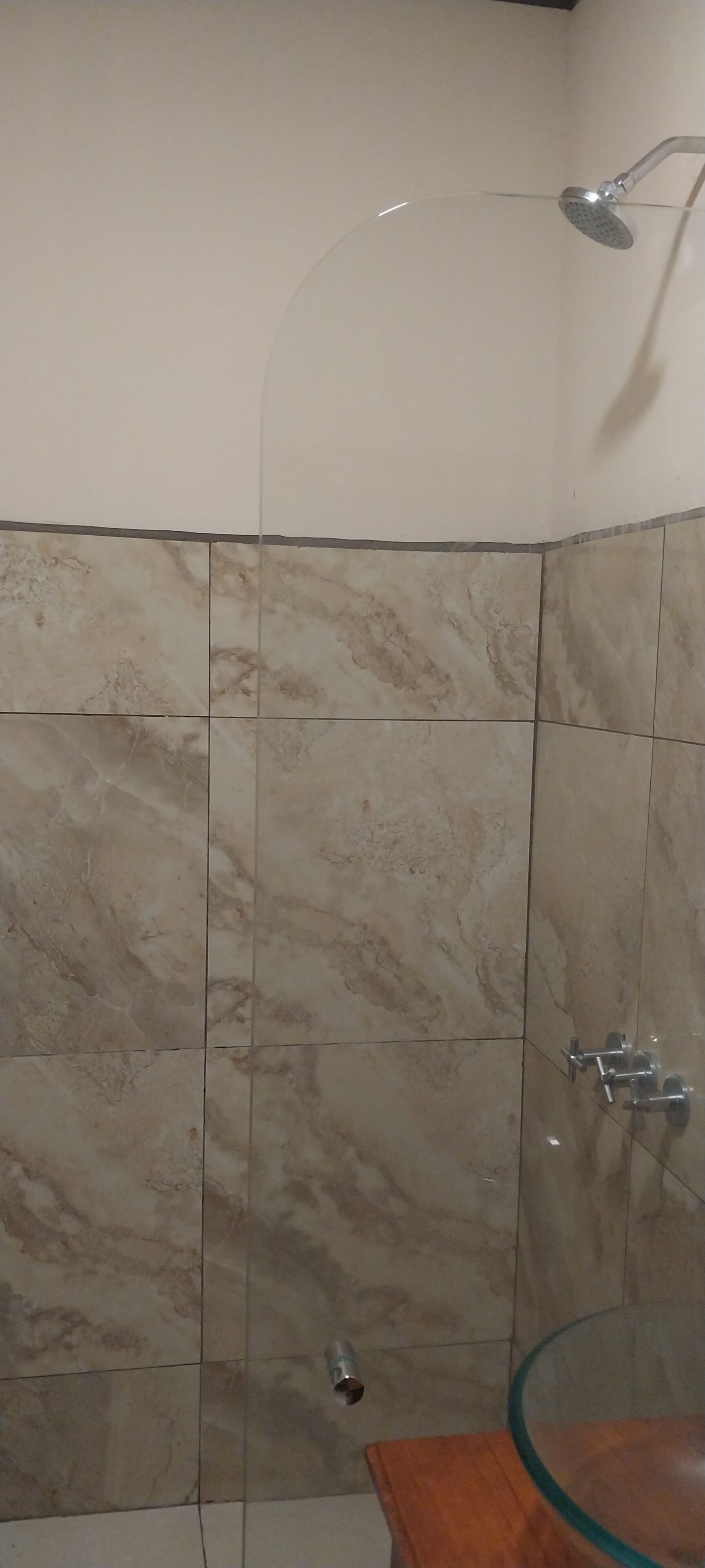 Un baño con cabina de ducha de vidrio, baldosas de mármol y tocador de madera.