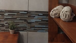 Un baño con tocador de madera, salpicadero de azulejos y un perchero.