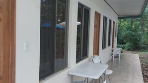 Un edificio con grandes ventanales, una puerta de madera y un pequeño patio con una mesa y sillas.