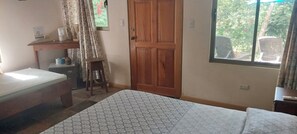 Cozy retreat with a bed, nightstand, and table by the window, offering a view of the outdoors.