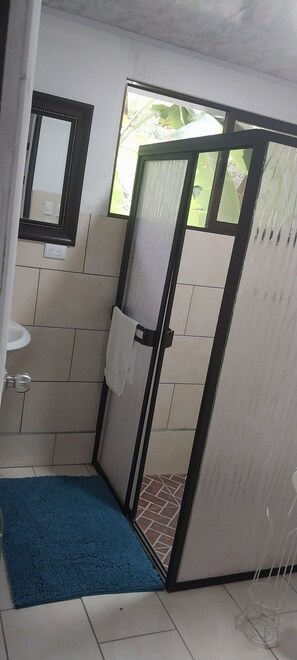 Bathroom features a sink, mirror, and towel rack, with a window offering a view of the surrounding greenery.