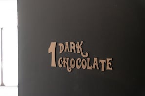 Una pared oscura con el texto "1 DARK CHOCOLATE" en una tipografía serif.
