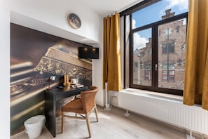 Una habitación moderna con escritorio, silla y un amplio ventanal con cortinas.