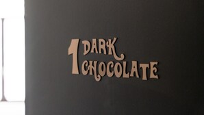 A dark wall with the text "1 DARK CHOCOLATE" in a serif font.