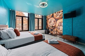Une chambre d’hôtel moderne avec deux lits, une grande fenêtre, un téléviseur fixé au mur et une vue sur la ville.