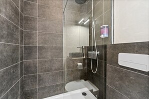 Een moderne badkamer met een douchecabine van glas, een toilet en een handdoekhouder.