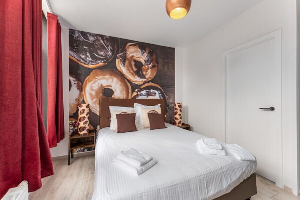 Een hotelkamer met een groot bed, rode gordijnen, een muurschildering en een witte deur.