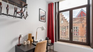 A modern room with a desk, chair, and a view of a brick building through a large window. - Homer Simpson's Donut Room - Steps from the Belfry (Brugge)