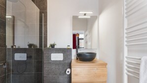 A modern bathroom with a glass-enclosed shower, a wooden vanity with a black bowl sink, and a white towel rack. - Homer Simpson's Donut Room - Steps from the Belfry (Brugge)