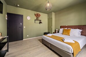 Une chambre d’hôtel avec un lit, une table de chevet et une étagère fixée au mur.