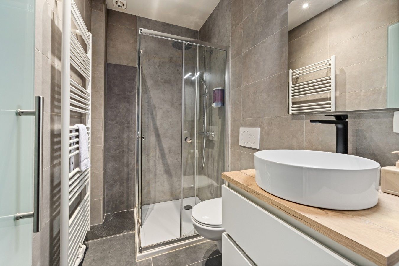 A modern bathroom with a glass-enclosed shower, a white sink, and a toilet.