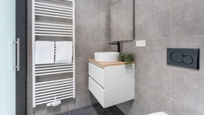 Une salle de bain moderne avec un meuble-lavabo blanc, un porte-serviettes, un miroir et un radiateur fixé au mur.