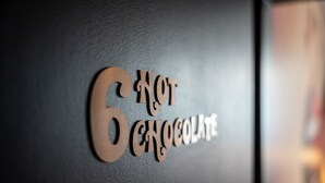 Un mur sur lequel on peut lire, en lettres de bois, le texte suivant : « 6, PAS DU CHOCOLAT ».