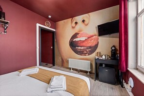 A hotel room with a bed, a large wall mural, a desk with a computer, and a radiator. - The Hot Chocolate Room by Charlie`s Choco Factory (Brugge)