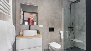 Une salle de bain moderne avec un lavabo blanc, des toilettes et une douche à parois de verre.
