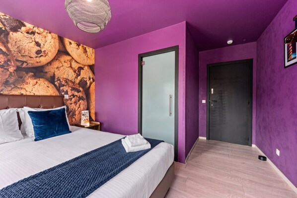 Un dormitorio moderno con una cama grande, cabecera con diseño texturizado, lámpara de pared y puerta con panel de vidrio esmerilado.