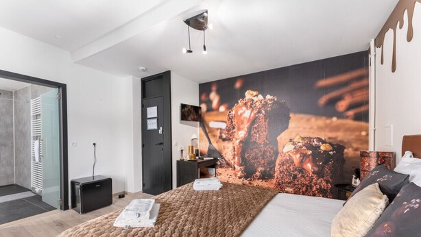 Una habitación de hotel moderna con una cama grande, una mesita de noche, un escritorio y un ventanal amplio.