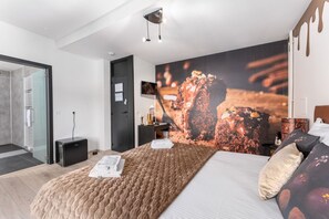 Una camera d'albergo moderna con un letto grande, un comodino, una scrivania e un'ampia finestra.